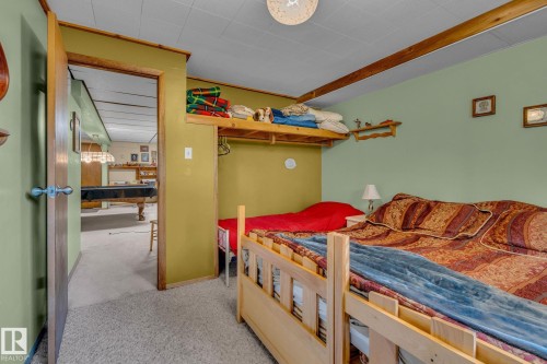 This room features light green walls, a light-colored carpet, and exposed wooden beams on the ceiling - 60017 Range Road 42, Rural Barrhead County, AB - Indoor Photo Showing Bedroom