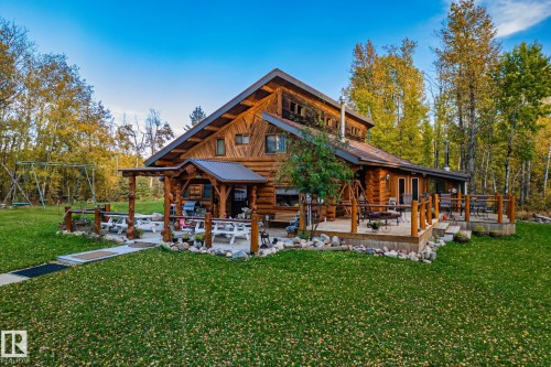 The property features a log cabin style exterior with a prominent A-frame roof - 60017 Range Road 42, Rural Barrhead County, AB - Outdoor With Deck Patio Veranda