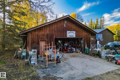 The property features a wood-sided outbuilding with an open garage bay and a prominent sign - 60017 Range Road 42, Rural Barrhead County, AB - Outdoor