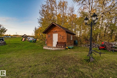 This property features a rustic cabin with a white door and a small porch - 60017 Range Road 42, Rural Barrhead County, AB - Outdoor