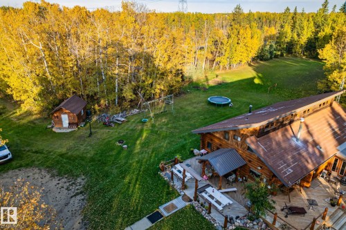 The property features an extensive yard with a well-maintained lawn and mature trees, offering a serene environment - 60017 Range Road 42, Rural Barrhead County, AB - Outdoor