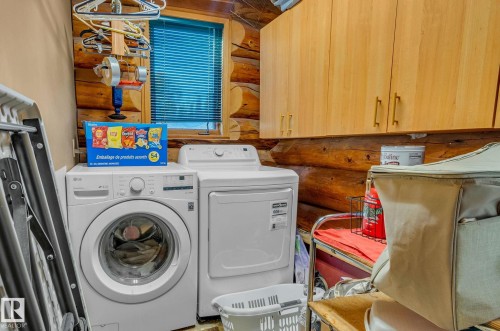 Laundry area featuring a front-loading washing machine, a dryer, and light wood cabinetry for storage - 60017 Range Road 42, Rural Barrhead County, AB - Indoor Photo Showing Laundry Room