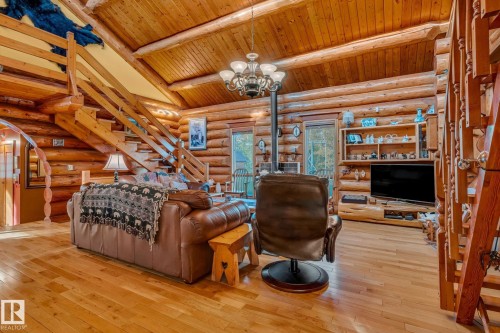 This property features log walls, light hardwood floors, and a wood ceiling with exposed beams - 60017 Range Road 42, Rural Barrhead County, AB - Indoor