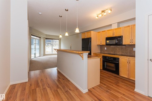 Open concept living area featuring hardwood flooring in the kitchen, a built-in oven, and a kitchen island with pendant lighting - 415 10503 98 Avenue, Edmonton, AB - Indoor Photo Showing Kitchen