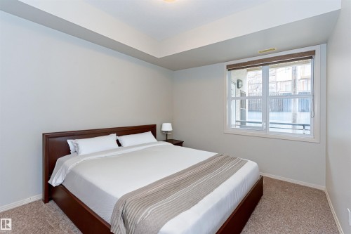This bedroom features a window providing natural light, light-colored walls, and carpeting - 415 10503 98 Avenue, Edmonton, AB - Indoor Photo Showing Bedroom