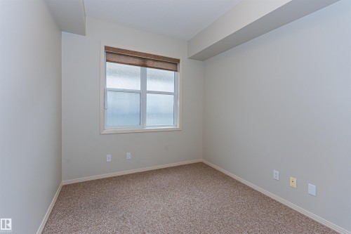 This room features light-colored walls, patterned carpeting, and a window with a blind - 415 10503 98 Avenue, Edmonton, AB - Indoor Photo Showing Other Room