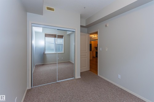 This room features a mirrored closet, carpeted flooring, and a window with blinds - 415 10503 98 Avenue, Edmonton, AB - Indoor Photo Showing Other Room