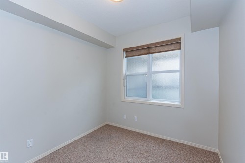 This room features light-colored walls, patterned carpeting, and a window with a brown blind - 415 10503 98 Avenue, Edmonton, AB - Indoor Photo Showing Other Room