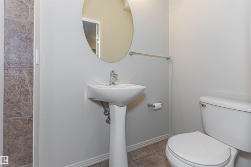 Bathroom featuring a pedestal sink with a chrome faucet, a white toilet, and a circular mirror - 415 10503 98 Avenue, Edmonton, AB - Indoor Photo Showing Bathroom