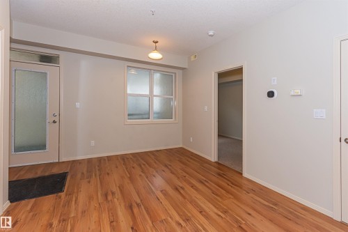 The property features wood flooring, a window with frosted panes, and a door with a frosted glass insert - 415 10503 98 Avenue, Edmonton, AB - Indoor Photo Showing Other Room