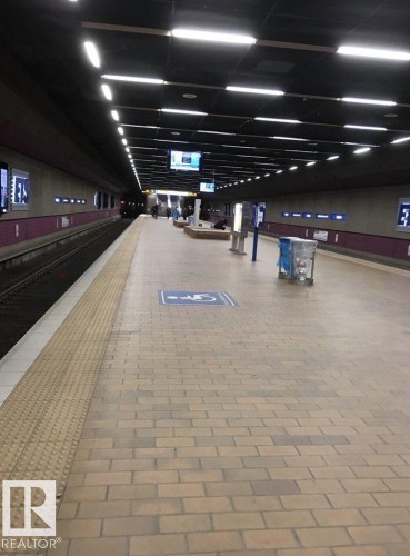 Conveniently located within a community providing easy access to public transit, this station features a spacious platform with brick-style paving, overhead lighting, and digital information displays - 1701 10024 Jasper Avenue, Edmonton, AB - Indoor Photo Showing Garage
