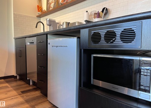 The kitchen features wood-look flooring, a white subway tile backsplash, a black gooseneck faucet, a built-in dishwasher, and a microwave - 1701 10024 Jasper Avenue, Edmonton, AB - Indoor
