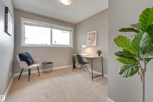 This room features light-colored carpeting, neutral painted walls, and a large window providing natural light - 13211 104 Street, Edmonton, AB - Indoor
