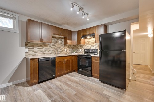 Well-appointed kitchen featuring wood cabinetry, a mosaic tile backsplash, black appliances, and a window providing natural light - 13211 104 Street, Edmonton, AB - Indoor Photo Showing Kitchen