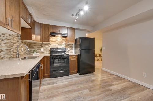 Kitchen featuring wood cabinetry, a tiled backsplash, and an L-shaped countertop - 13211 104 Street, Edmonton, AB - Indoor Photo Showing Kitchen
