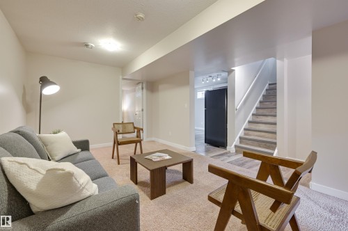 The living area features light-colored carpeting, a floor lamp, and a staircase with a handrail - 13211 104 Street, Edmonton, AB - Indoor Photo Showing Other Room