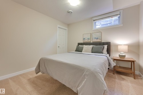 This room features neutral-toned walls, a window with a white frame, and plush carpeting - 13211 104 Street, Edmonton, AB - Indoor Photo Showing Bedroom