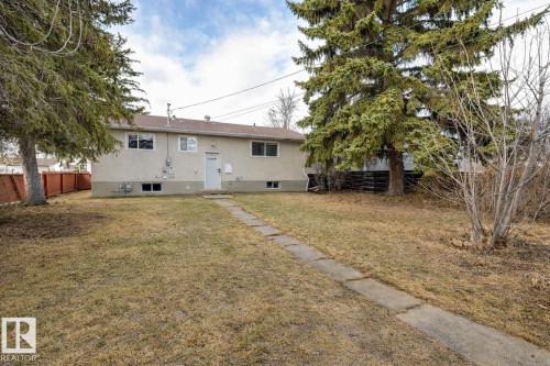 The property features a spacious yard with mature trees and a walkway leading to the rear entrance - 13211 104 Street, Edmonton, AB - Outdoor