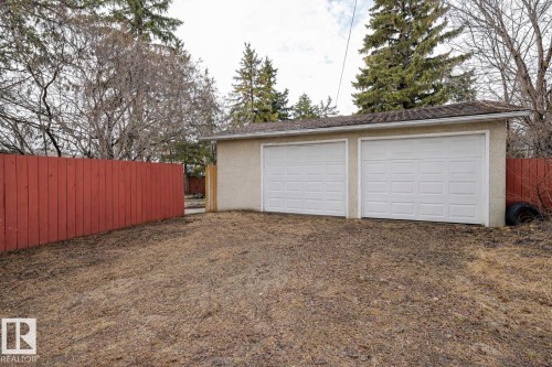The property includes a detached two-car garage with white garage doors and a red wooden fence - 13211 104 Street, Edmonton, AB - Outdoor