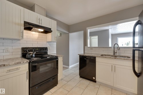 The kitchen features light-colored cabinetry, a subway tile backsplash, and granite-style countertops - 13211 104 Street, Edmonton, AB - Indoor Photo Showing Kitchen With Double Sink