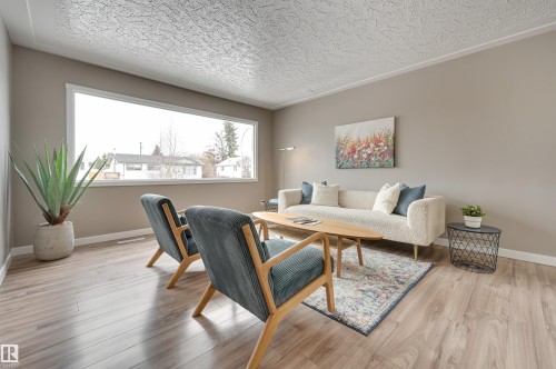 Living room with wide plank flooring, a large window, and light-colored walls - 13211 104 Street, Edmonton, AB - Indoor