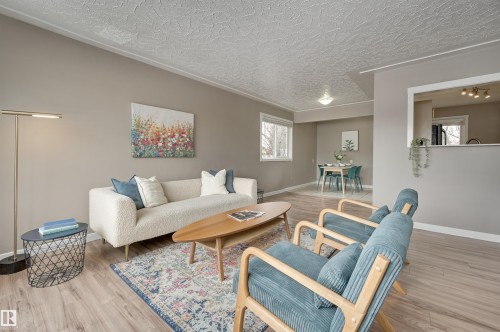 The living area features light-toned flooring, a window providing natural light, and a pass-through opening to another space - 13211 104 Street, Edmonton, AB - Indoor Photo Showing Living Room