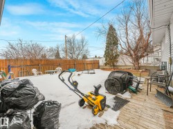 The property features a fenced backyard with a wooden deck and a mature tree - 
