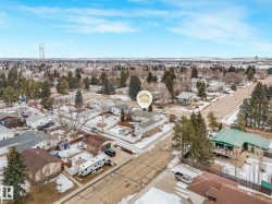 Aerial view of the residential area, featuring a mix of houses with varying roof styles and surrounding trees, with some visible patches of snow on the ground - 