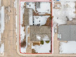 Aerial view showcasing the property's roof, front yard with a walkway, and a driveway leading to a detached structure - 