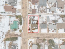 Aerial view of the property, outlined in red, situated within a residential neighborhood with visible streets and other structures - 