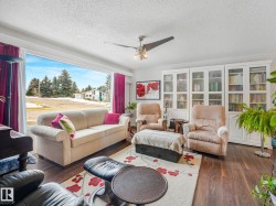 Living room featuring hardwood flooring, a large window providing natural light, and built-in white cabinets - 