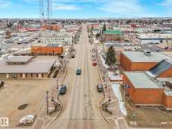 An aerial view of the property and its surrounding area, featuring a paved road, sidewalks with decorative patterns, and various commercial buildings - 