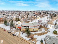 The property is centrally located within a developed community, featuring a building with a large roof and visible parking spaces - 