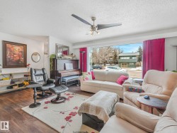 Living area featuring wood flooring, a ceiling fan, and a large window providing views of the exterior - 