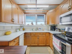 The kitchen features wood cabinetry, white countertops, a stainless steel microwave, and a black and stainless steel range - 