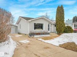 This property features a single-story home with light grey siding, a front entry with steps, and a large front window - 