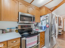The kitchen features wood cabinetry, stainless steel appliances including an oven and microwave, and white countertops - 