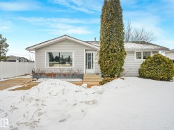 The property features light-colored siding, a white front door, and a prominent front window - 