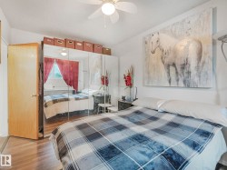 This room features wood flooring, a ceiling fan, and mirrored closet doors - 