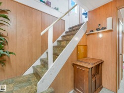 Staircase featuring wood paneling, tiled flooring, and a white handrail - 