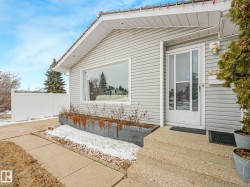 The property features light gray siding, a prominent front window, and a white front door with glass panels - 
