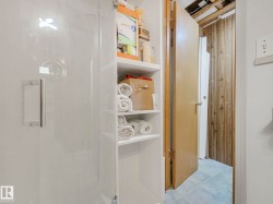 A white shower stall with a clear glass door and a stainless steel handle - 