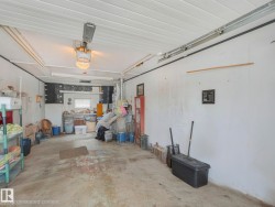 This property features a garage with a concrete floor and a ceiling with exposed beams - 