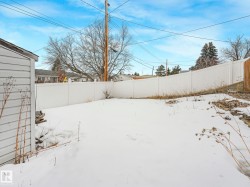 The property features an outdoor area with a white privacy fence and a white-sided outbuilding - 