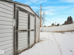The property features a white outdoor storage shed and a backyard area with a white privacy fence - 