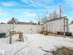 The property features a fenced yard with a white storage shed - 