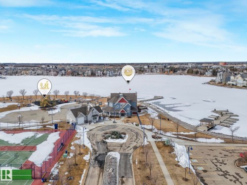 Aerial view showcasing the property's location by a large body of water, featuring a dock area with covered slips and a nearby tennis court - 8112 Summerside Grande Boulevard, Edmonton, AB - Outdoor With View
