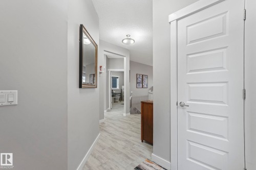 The hallway features light-toned flooring, white baseboards, and light grey walls - 8112 Summerside Grande Boulevard, Edmonton, AB - Indoor Photo Showing Other Room