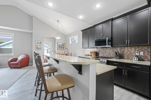 The property features a kitchen with dark cabinetry, stainless steel appliances, and a mosaic tile backsplash - 8112 Summerside Grande Boulevard, Edmonton, AB - Indoor Photo Showing Kitchen With Upgraded Kitchen
