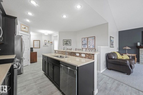 The property features an open kitchen with dark cabinetry, stainless steel appliances, and light countertops - 8112 Summerside Grande Boulevard, Edmonton, AB - Indoor Photo Showing Kitchen With Double Sink